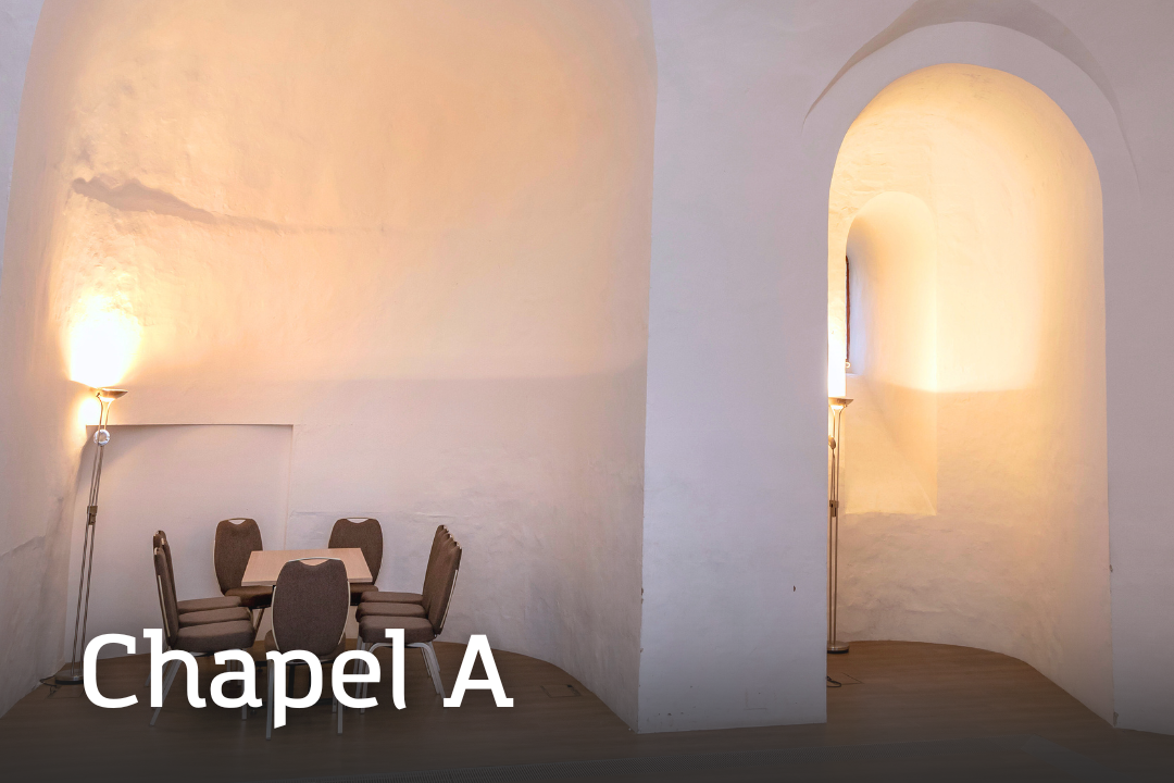 Chapel A Chapel A A softly lit chapel room with high, smooth white stone arches and a small round table surrounded by chairs beneath a tall alcove.